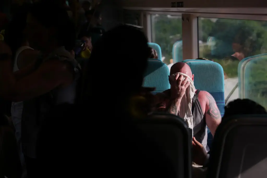 A man on a train wipes sweat from his face...