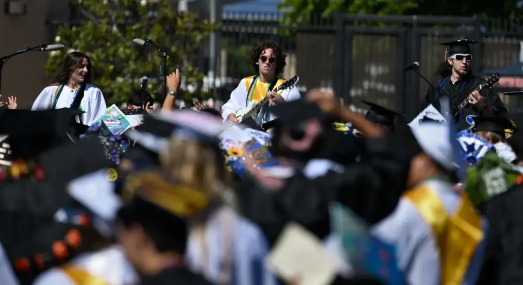 Graduates gather at the front of the stage as Brennan...