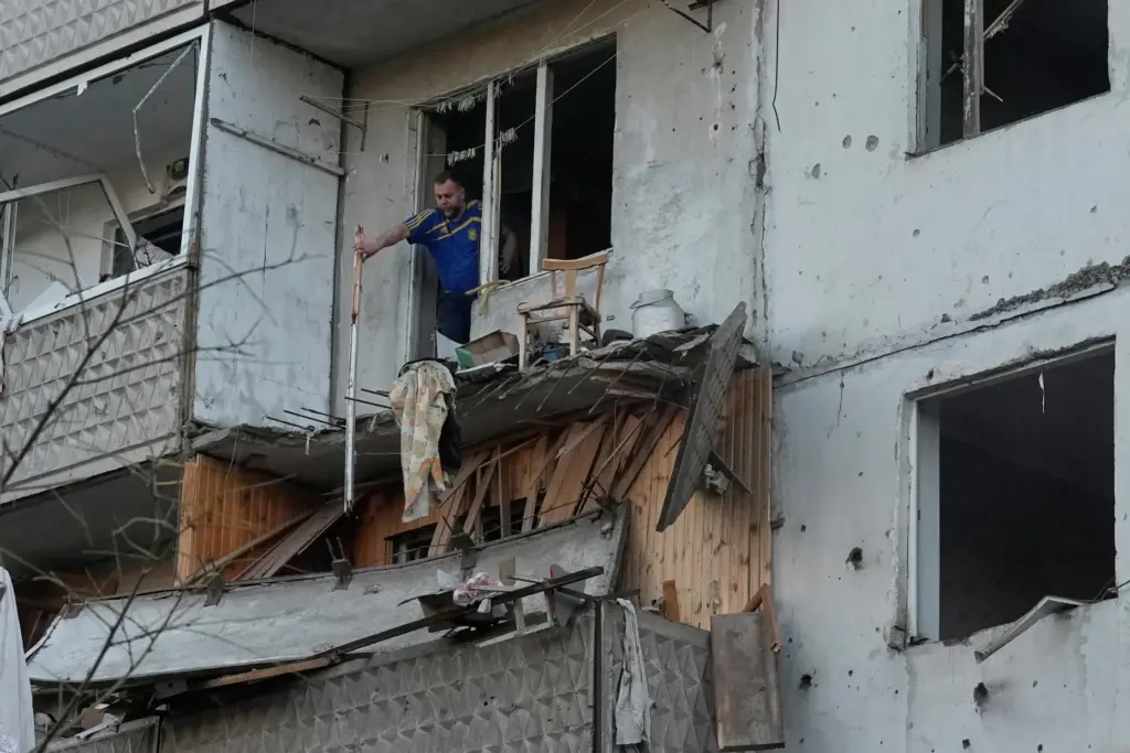 A man clears debris in his apartment building damaged after a Russian missile strike.