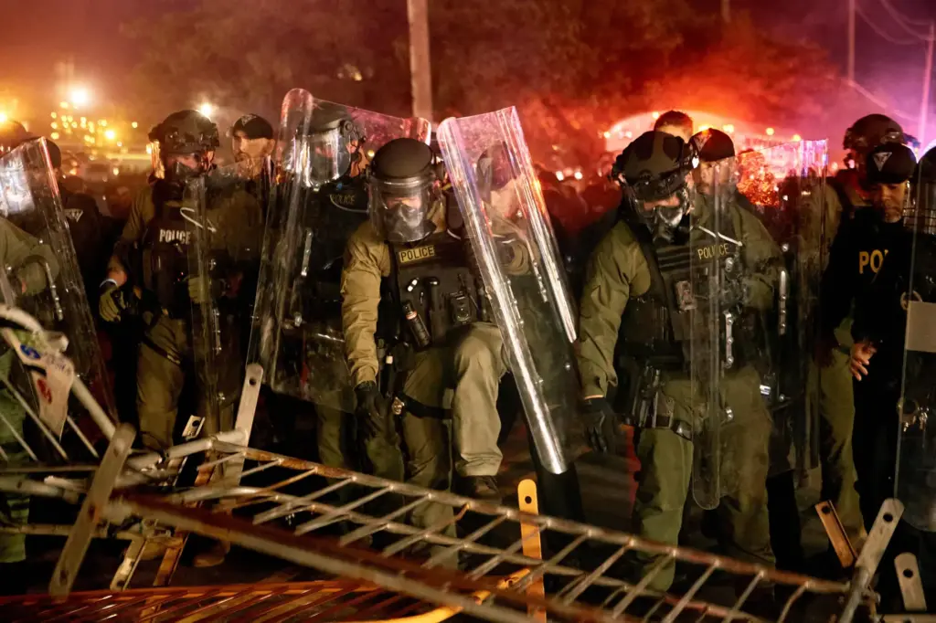 Police pass over a barricade as they clash with protesters.