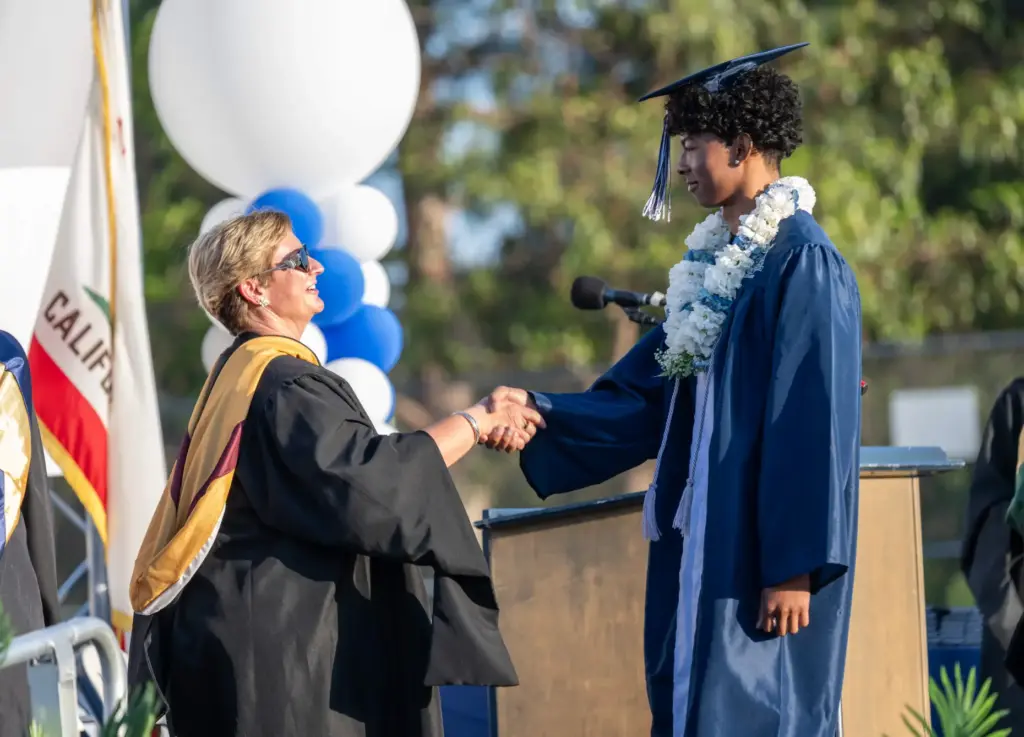 Markus Ashley shakes hands with Principal Alicia Foulk while walking...
