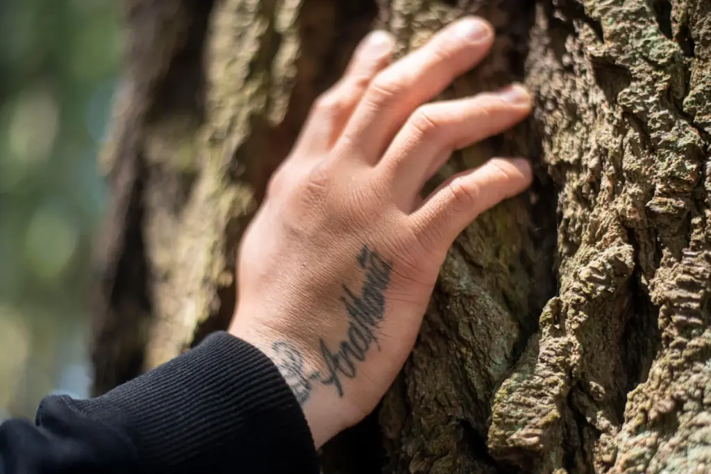 Gabriel Martinez Garcia rests his hand on a tree as his mother's name tattoo is visible.