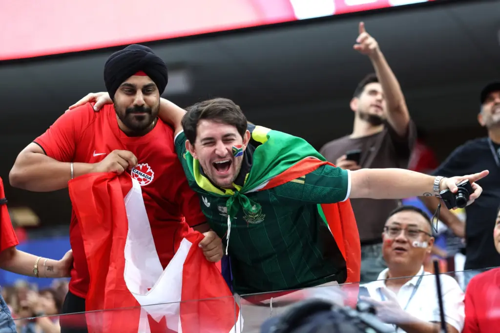 A Canada fan, left, and a South Africa fan react...