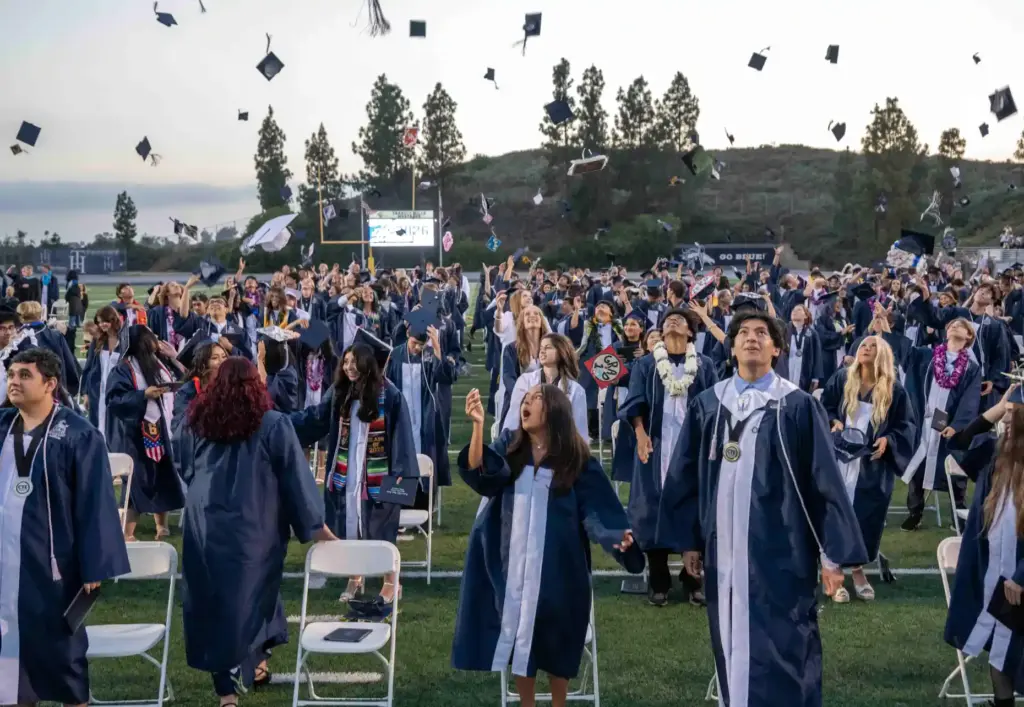 Graduates toss their caps in the air at the conclusion...