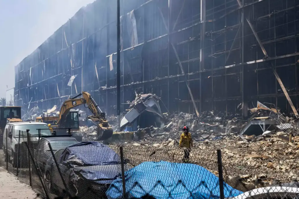 LAFD Captain Justin Horwedel walks past the smouldering remains of...