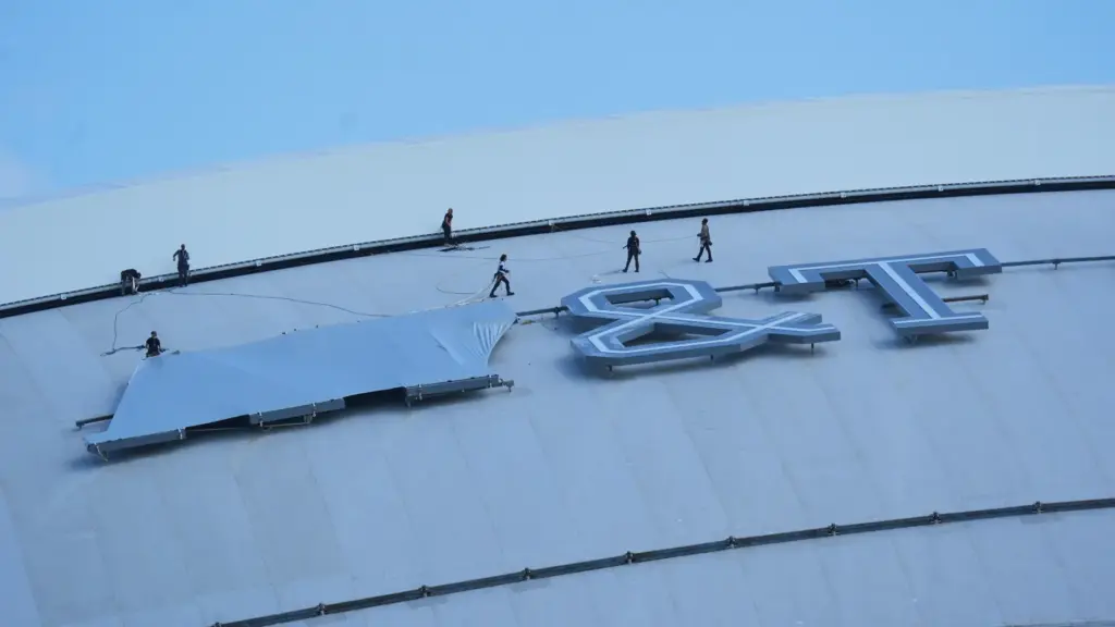 Workers cover signage on the exterior of AT&T Stadium, which...