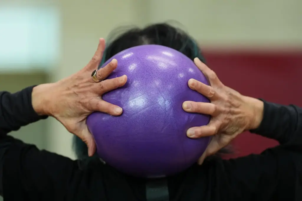 A participant grabs an exercise ball during a class for older adults.
