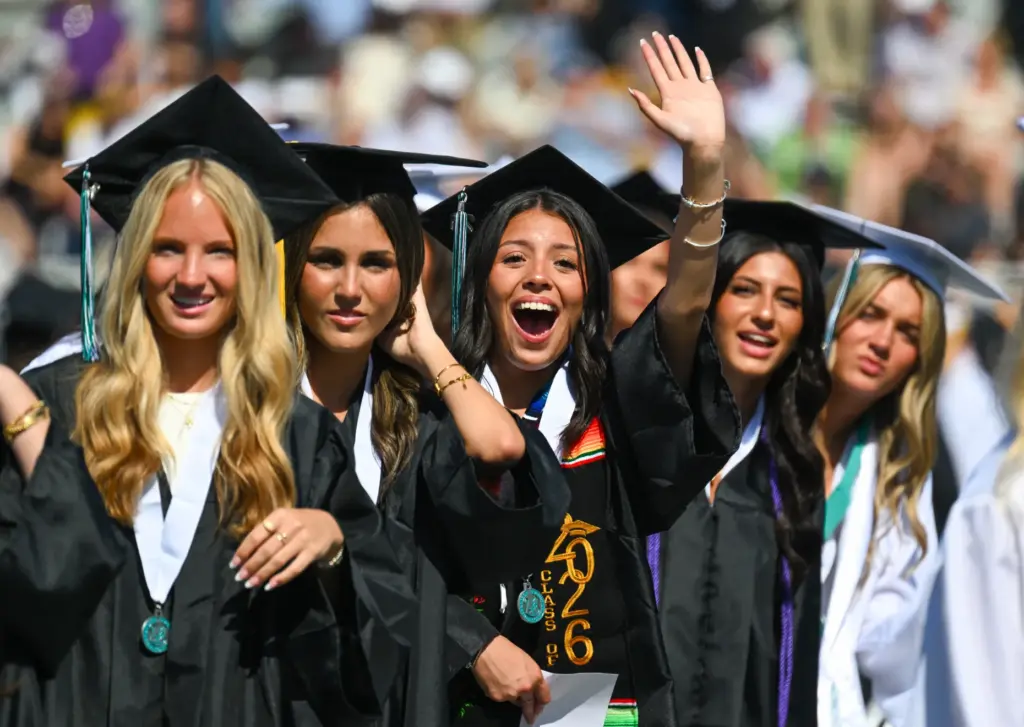 Graduate Lily Marie Arismendi, center, waves to the crowd during...