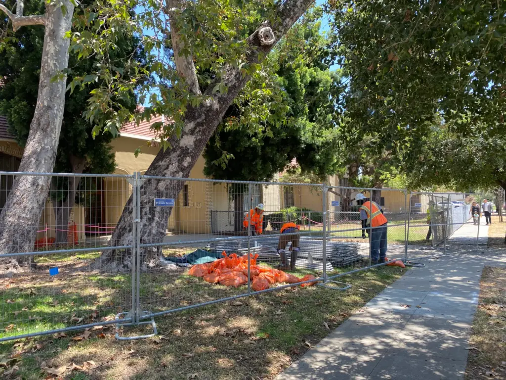 Workers set up fences around trees at the Pasadena Unified...