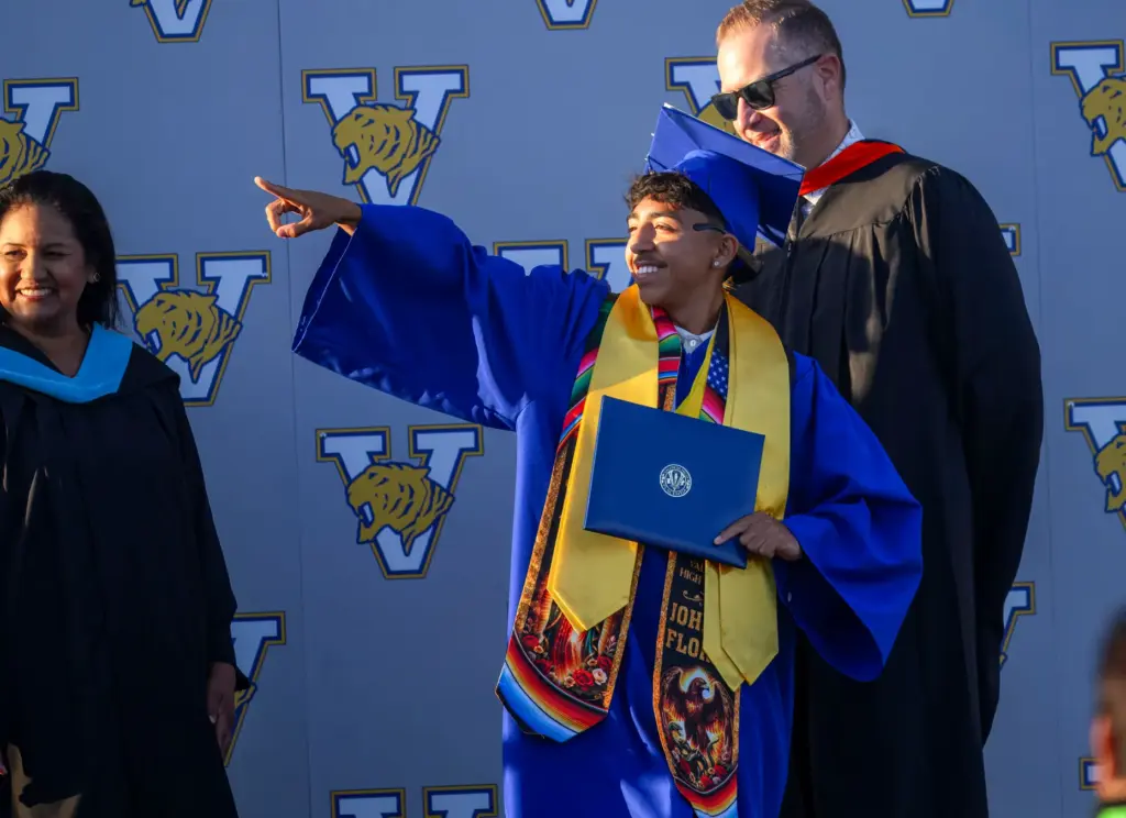 Graduate Johnny Flores motions to his family as he receives...