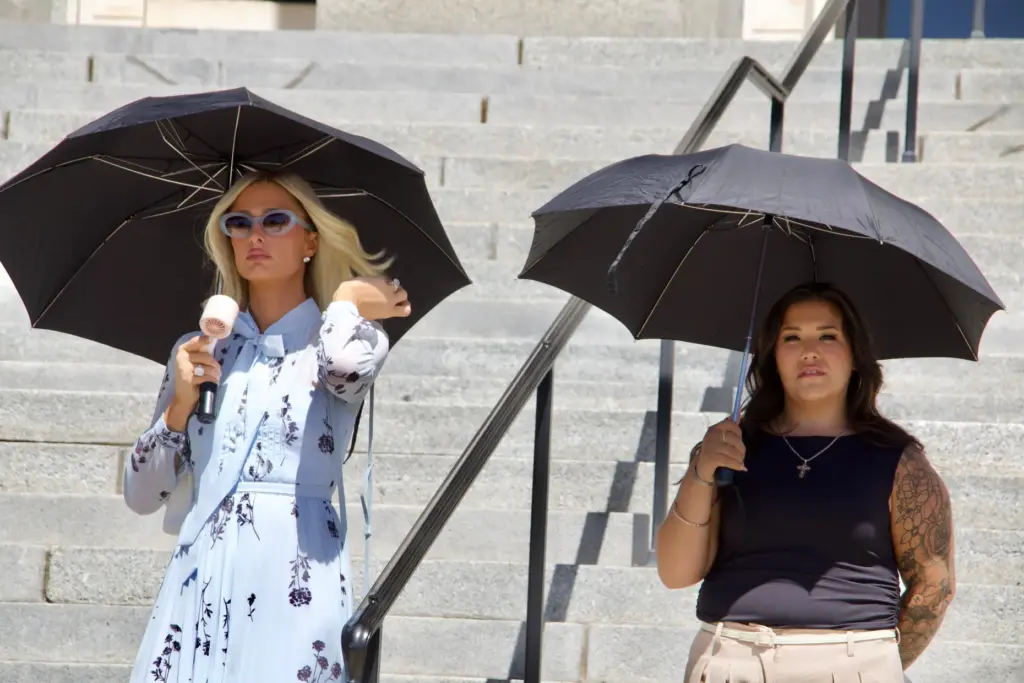 Paris Hilton stands alongside Aleah Corona during a news conference.