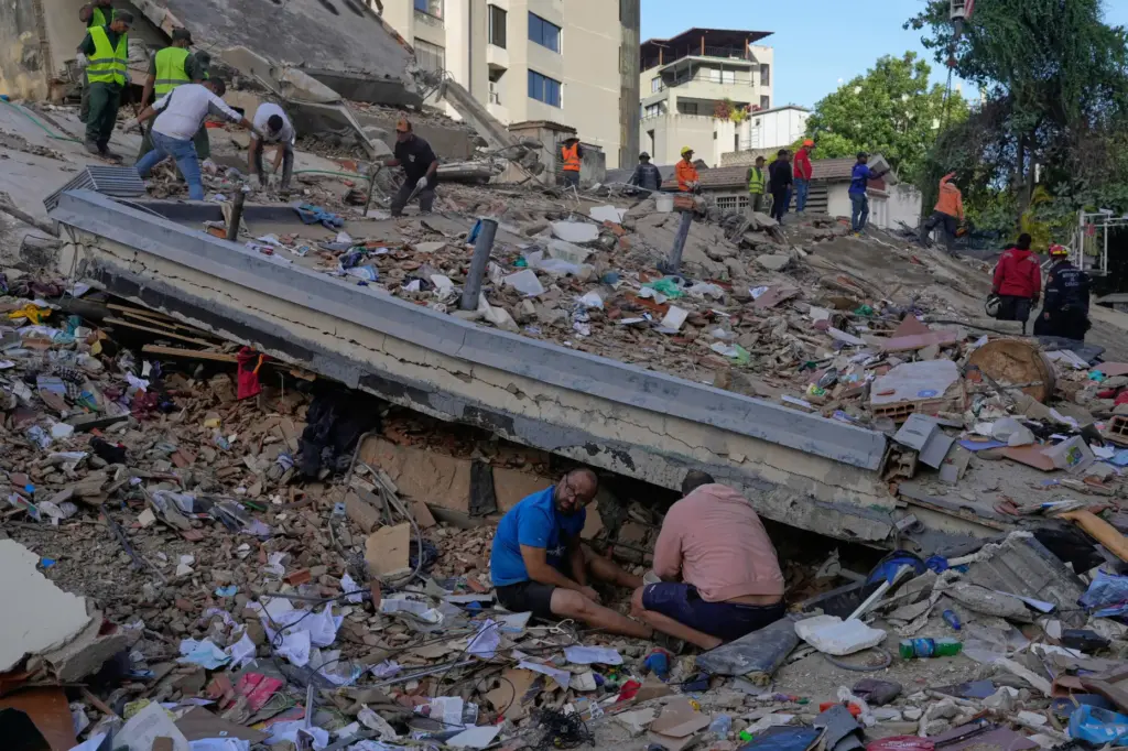 Residents and rescue workers search through the rubble of a...