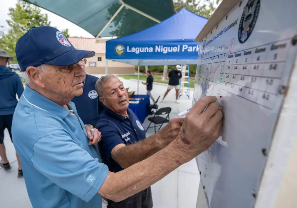 Gino Leo of Lake Forest, left, updates a scoreboard after...