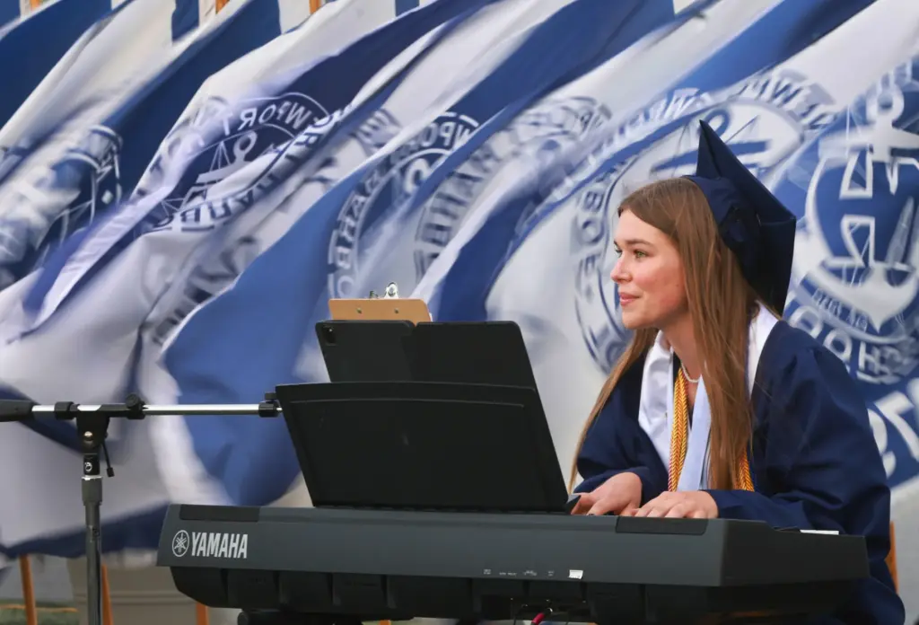 As Flags blow in the background, Graduate, Shelby Kliewer performs,...