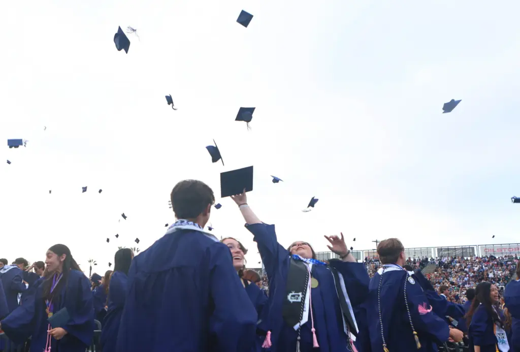 Graduates throw their mortar boards after graduating from Newport Harbor...