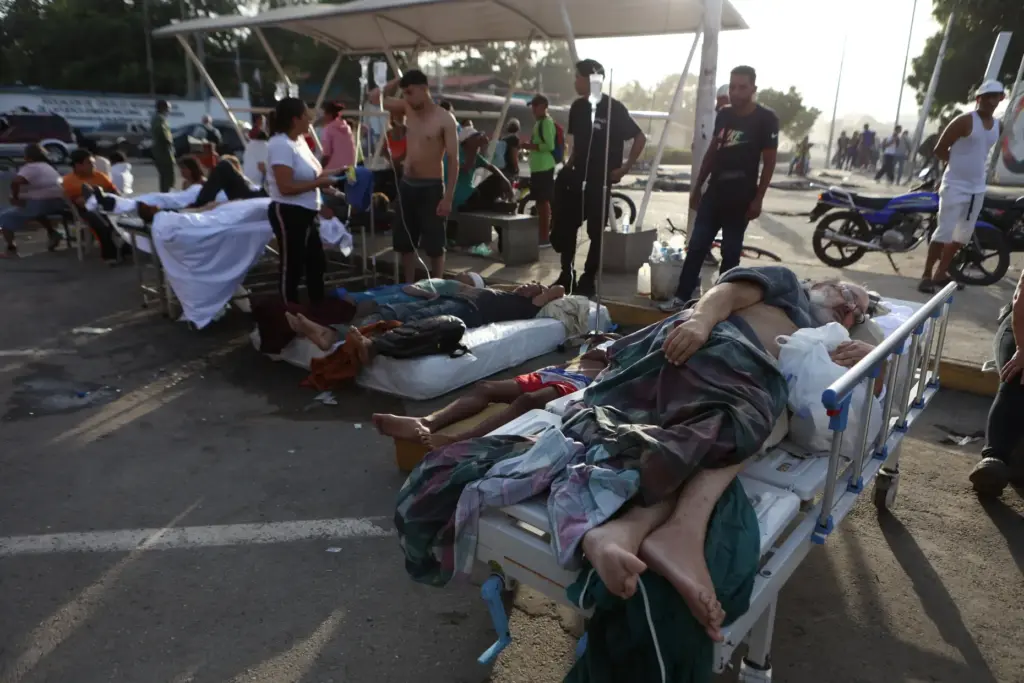 Patients lie outside a hospital evacuated after it was damaged...