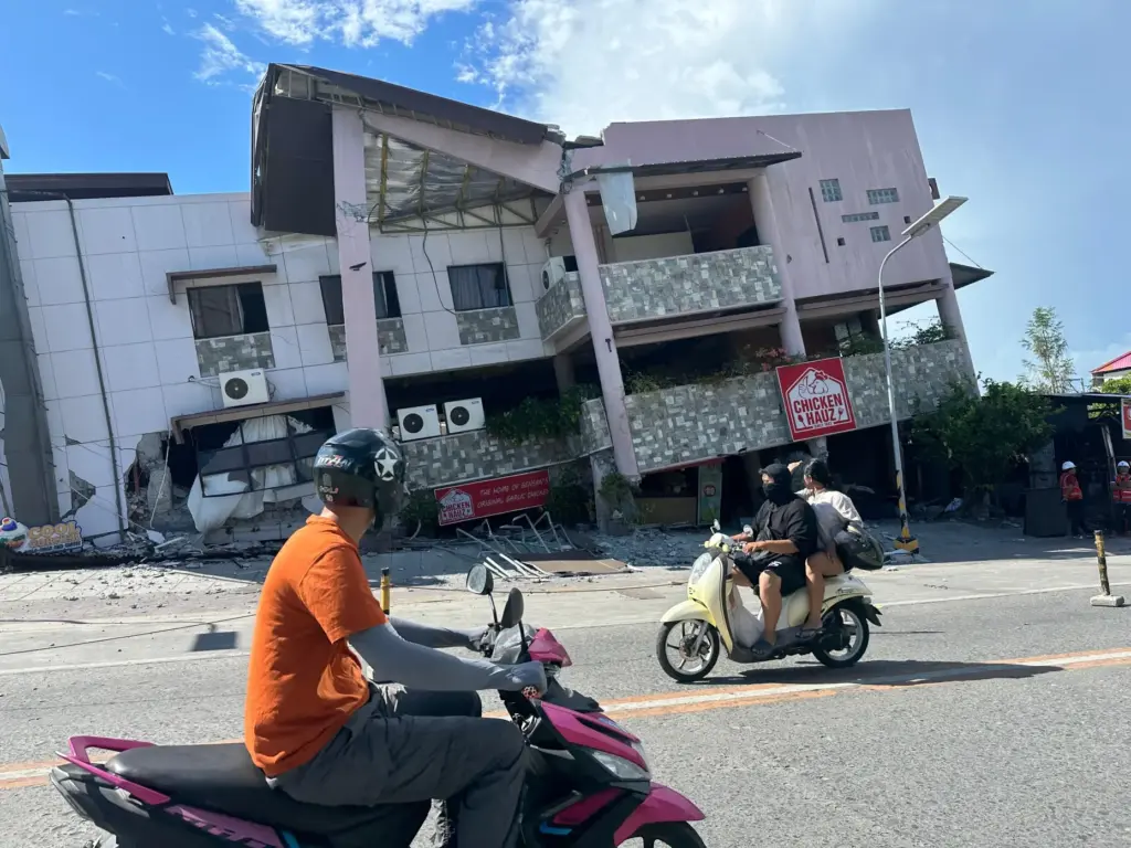 Residents pass by a collapsed structure after an earthquake in...