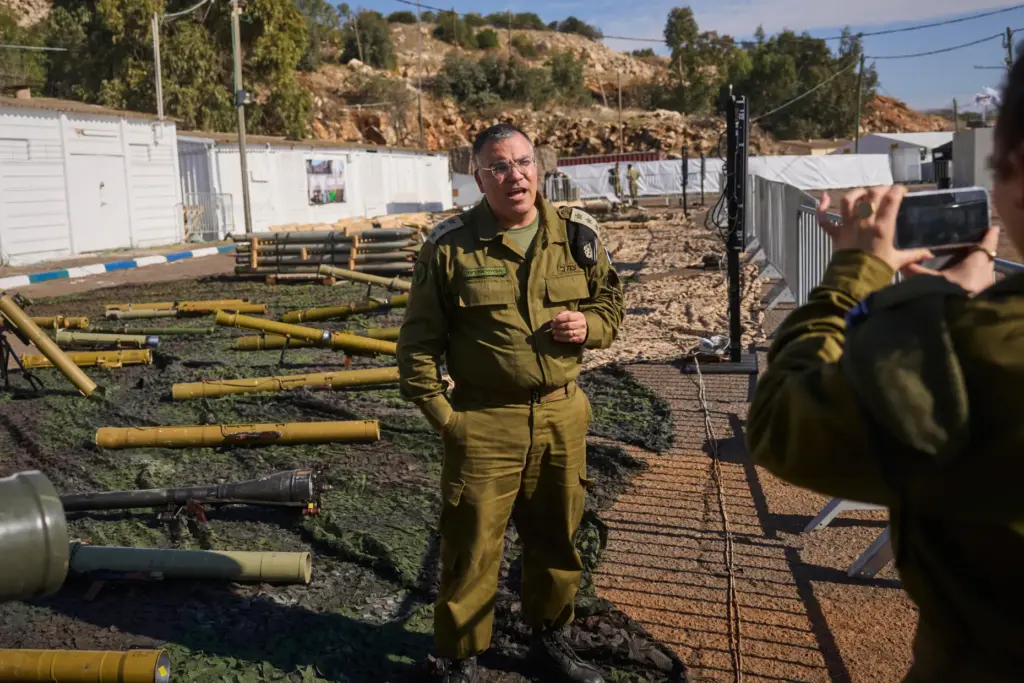 Avichay Adraee, Israeli military Arabic spokesman, stands beside weapons the army says were seized from Hezbollah.