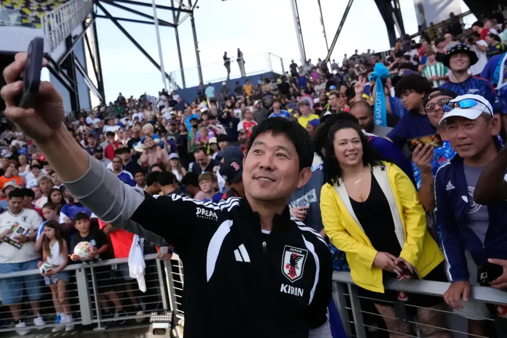 Japan head coach Hajime Moriyasu takes a picture with fans.