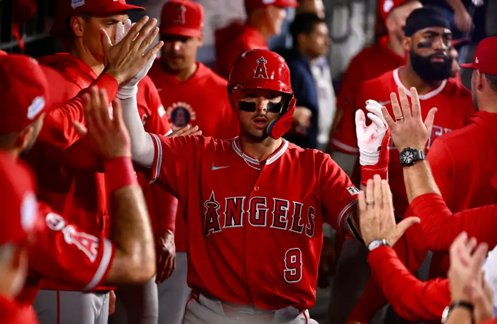 Zach Neto #9 of the Angels high fives teammates after...