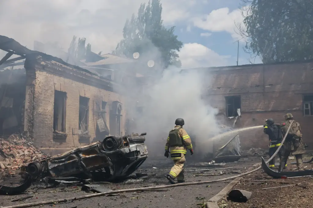 Rescue workers put out a fire at a building destroyed...