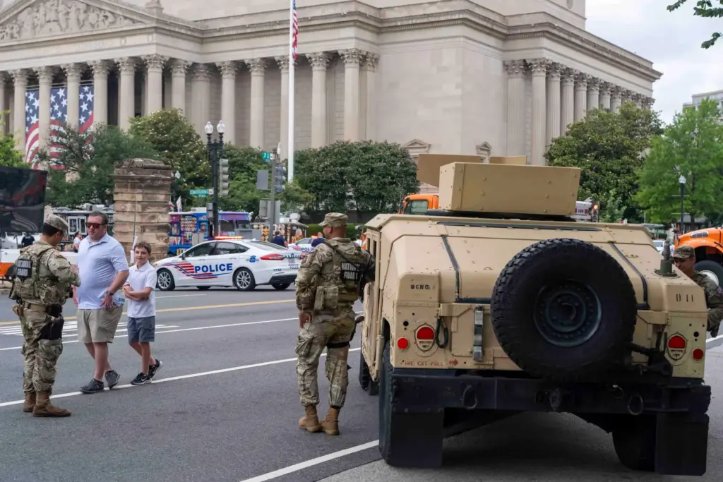 People walk past members of the National Guard stationed outside...
