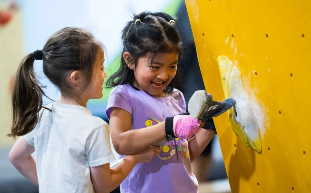 Lyanna Su, left, and Cassie Ni, brush chalk off holds...