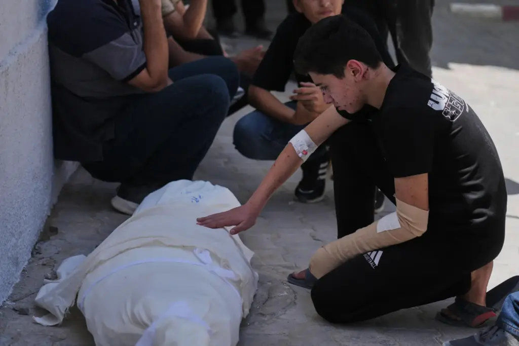 Omar Klaub, injured in an Israeli strike, mourns beside the...