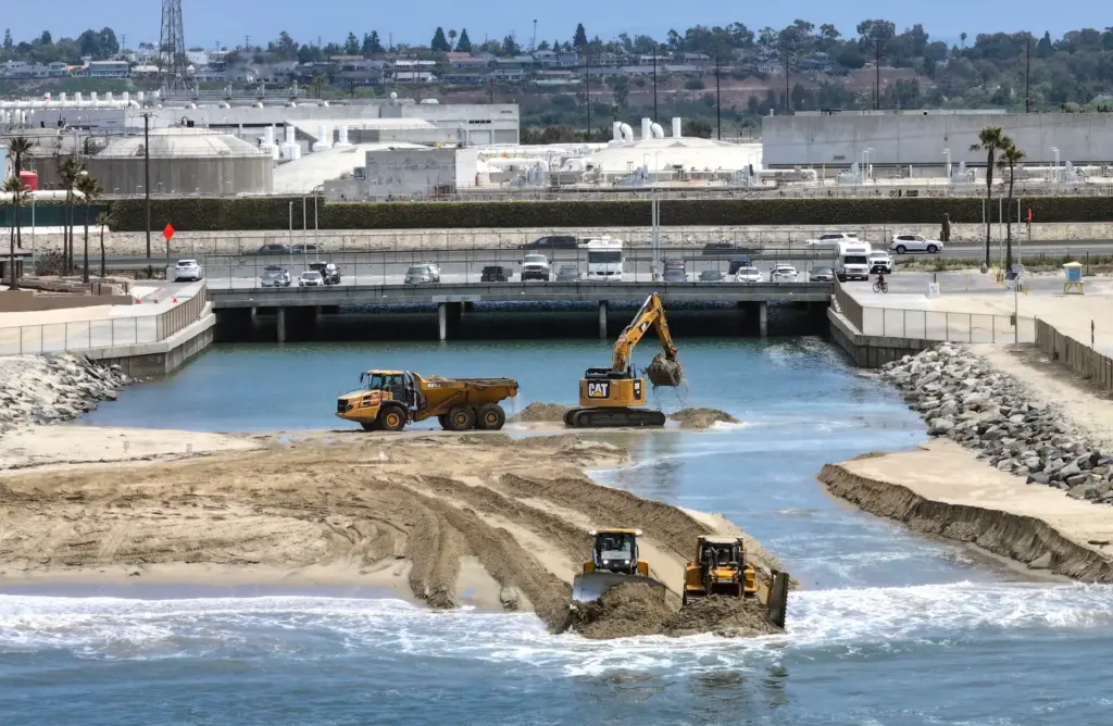 Workers clear sand from the opening between the Talbert Marsh...