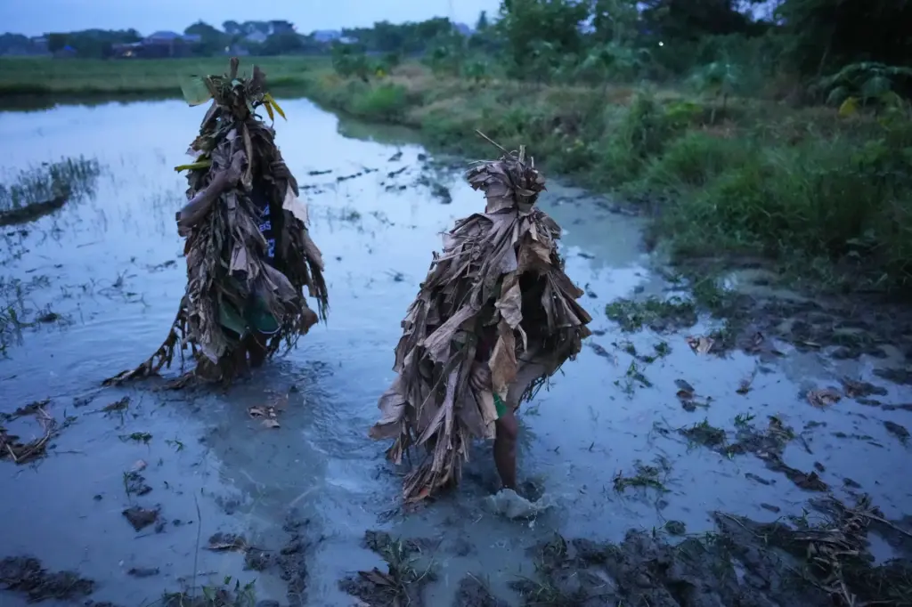 Catholic devotees cover themselves with mud and dried banana leaves...