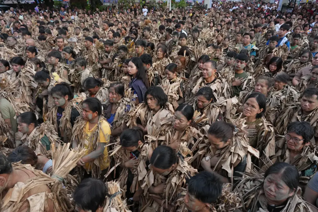 Catholic devotee covered in mud and dried banana leaves participate...