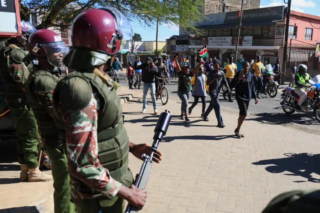 Anti-riot police officers stand by as demonstrators protest.