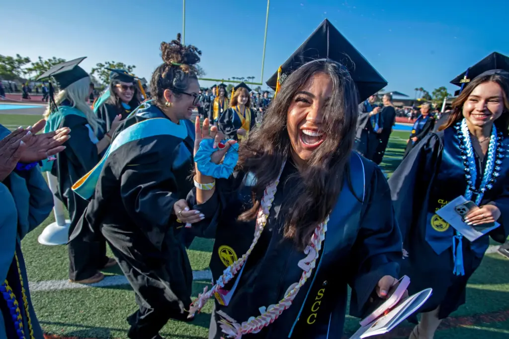 Graduate Mya Alvarez (center) celebrates with faculty member Sarah Shawesh...