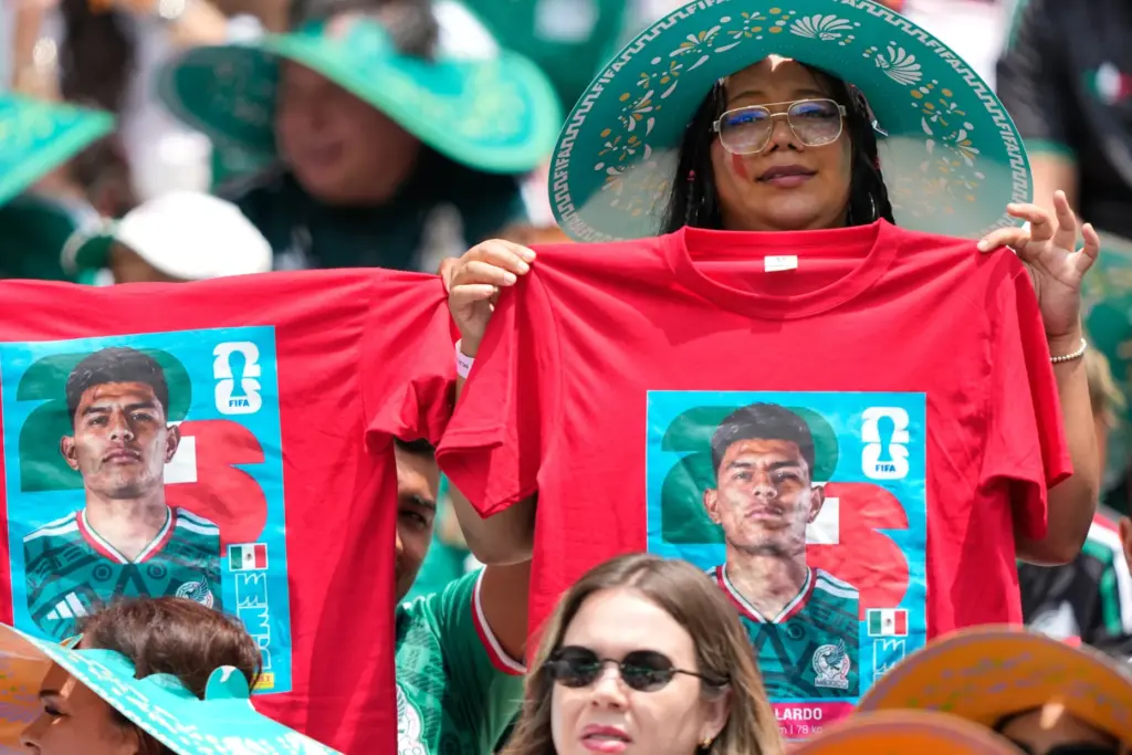 Mexico fans on the stands hold t-shirts with a picture...