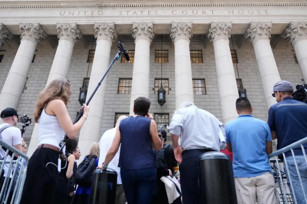 Reporters and others wait outside of a federal courthouse during...