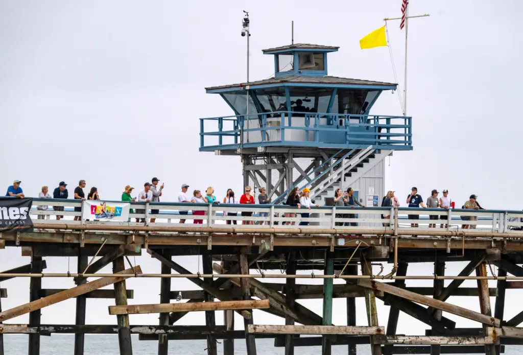 Fans watch the action from the San Clemente Pier during...
