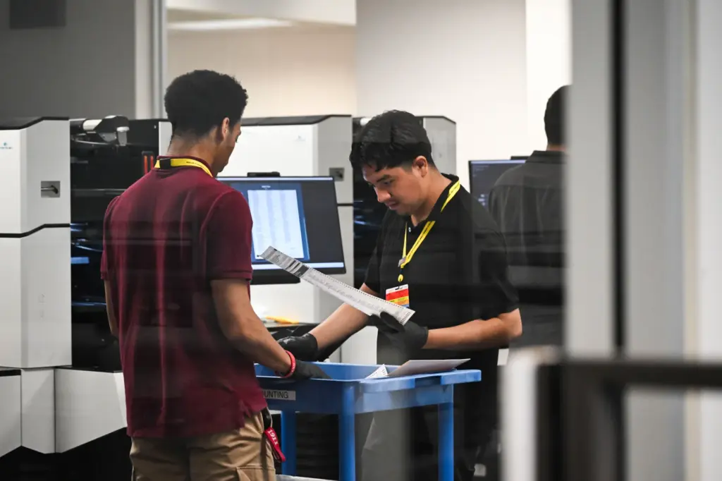 Temporary election assistants monitor and count ballots as they pass...