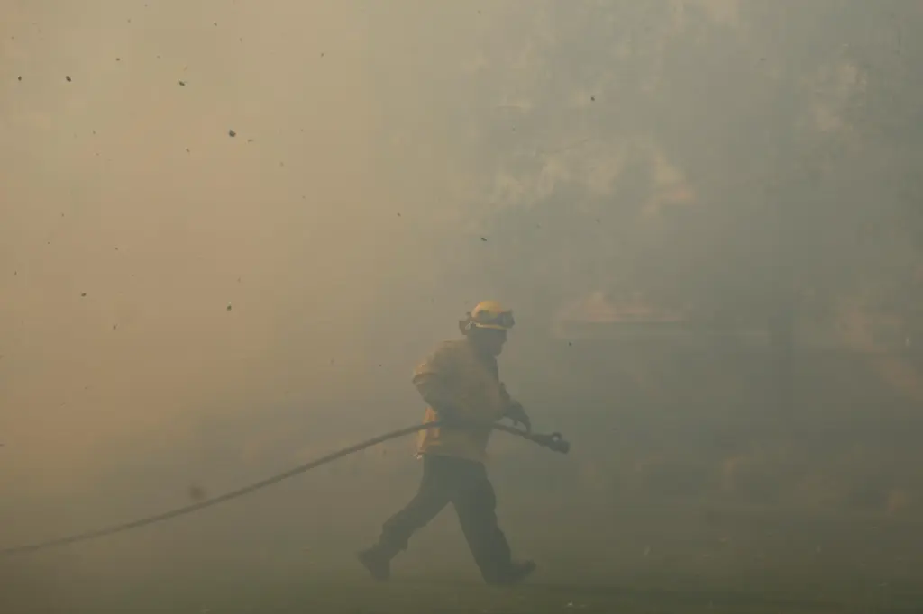 FILE – A firefighter works as the Sandy Fire approaches...