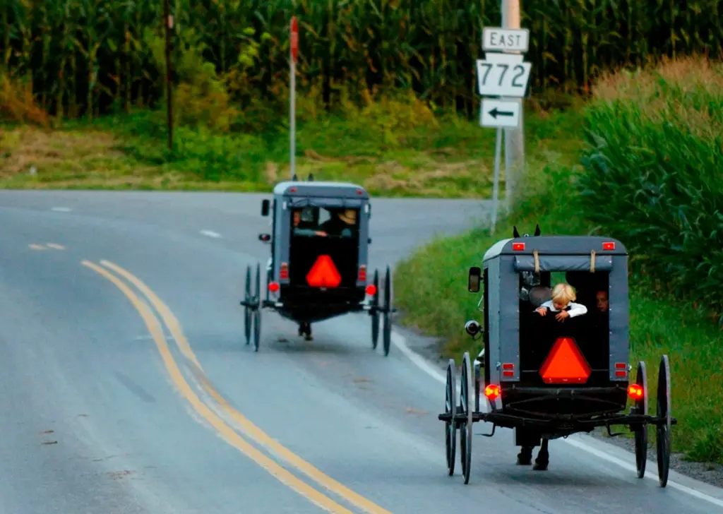 Amish horse-drawn buggies trot along the roads of Intercourse, Pennsylvania....