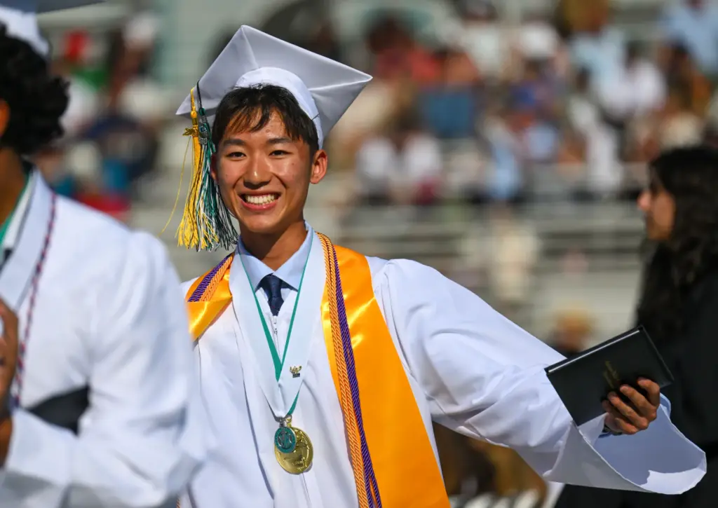 Graduate Andrew Oh greets friends after getting his diploma during...