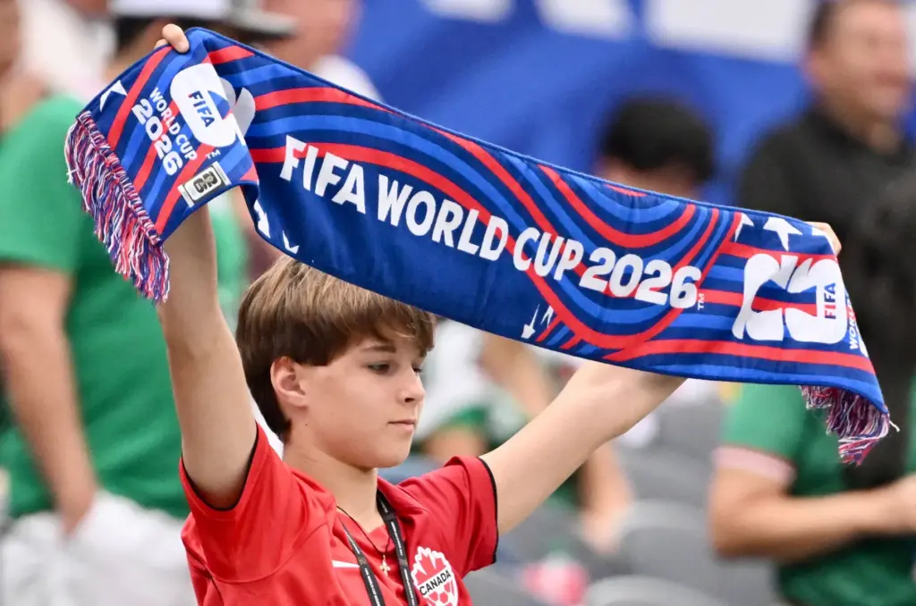 A young soccer fan holds his scarf up as the...