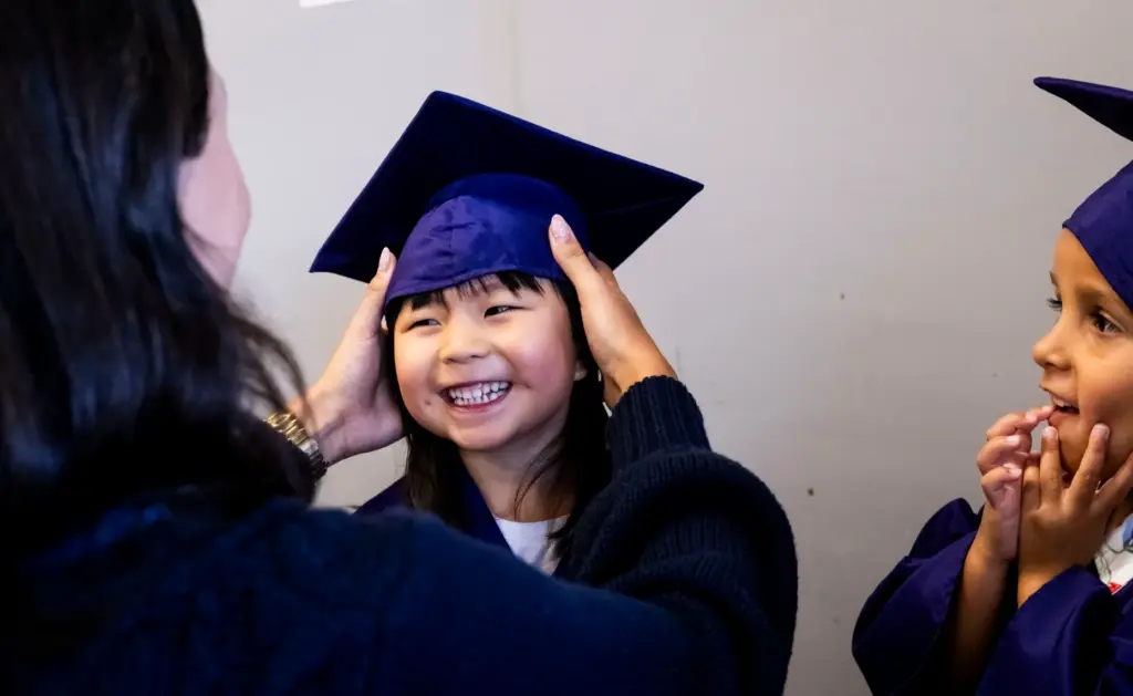 Ally Lam has her cap adjusted before her preschool promotion...