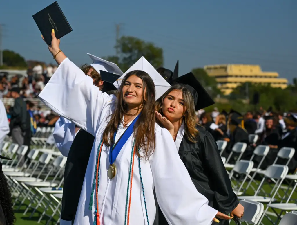 Graduate Lilly Stroj, center, gestures to the crowd as classmate...