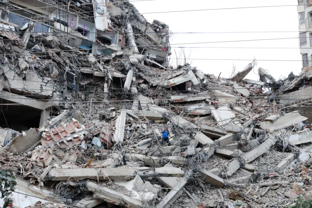 A man walks among the rubble of a building that...
