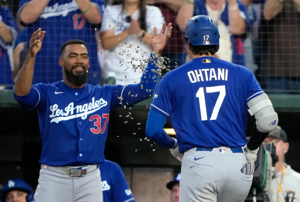Dodgers star Shohei Ohtani, right, gets showered with sunflower seeds...