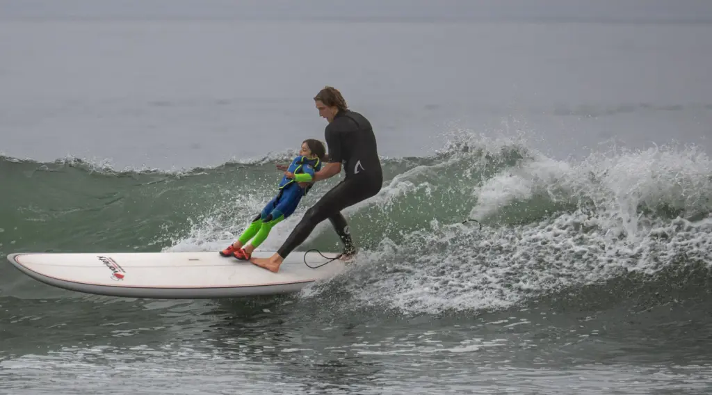 Surfers Healing volunteer Blake Michaels helps 5-year-old Luka Richey stay...