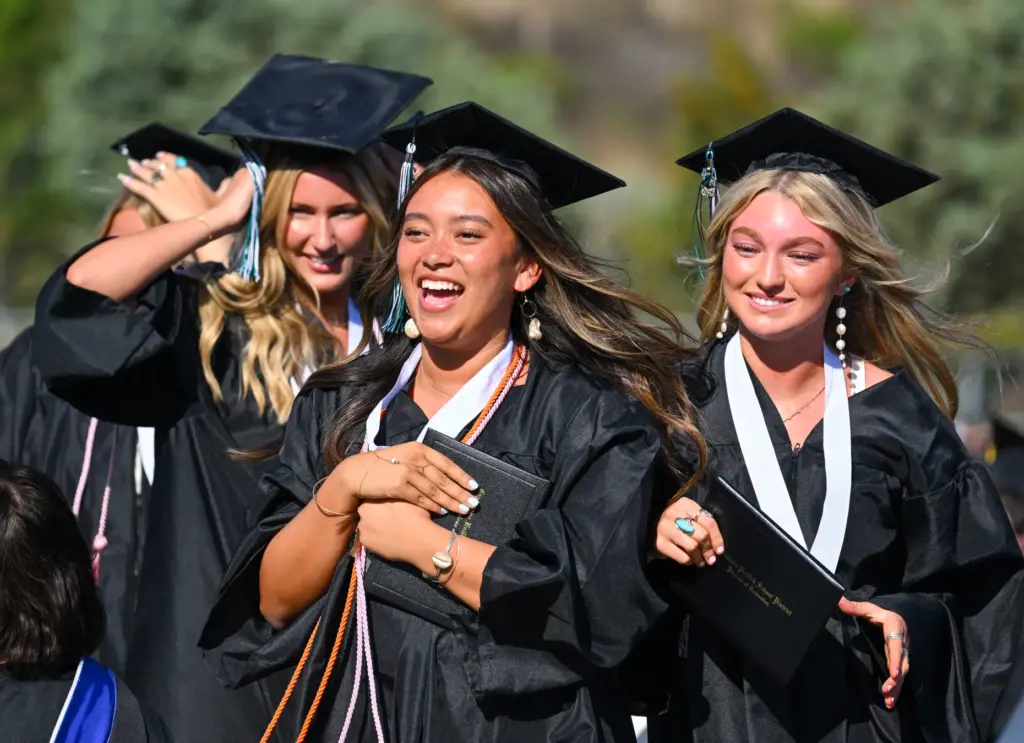 Graduates Chloe Hilario, center, and Leah Andrews, right, join friends...