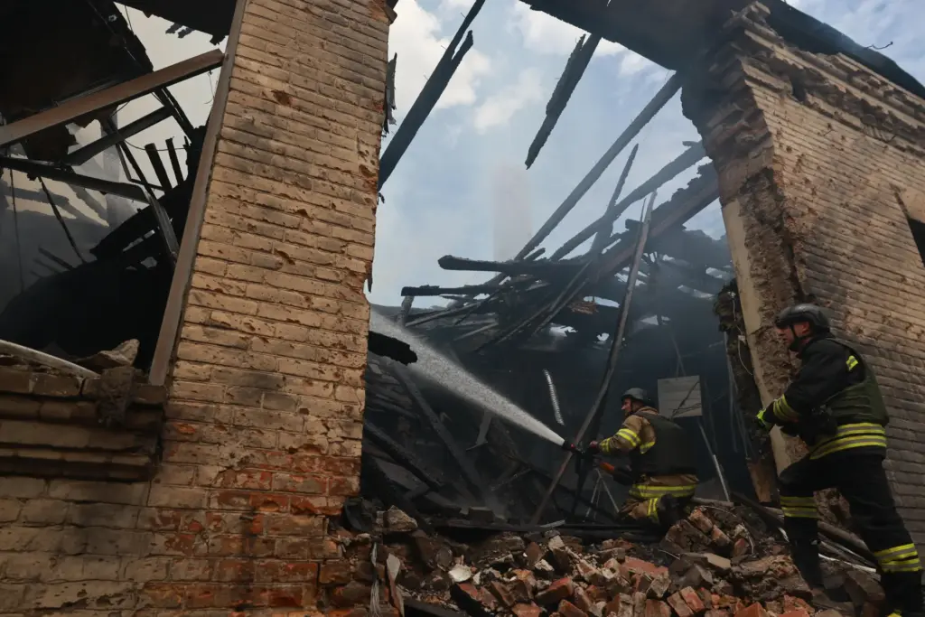 Rescue workers put out a fire at a building destroyed...