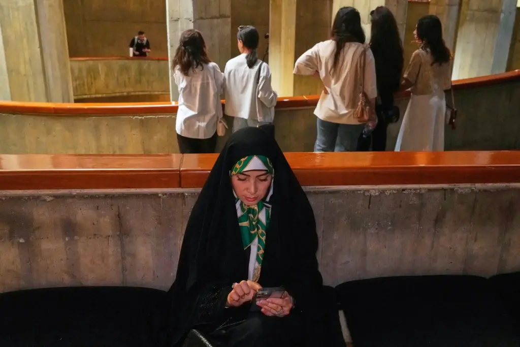 A woman checks her cellphone as visitors attend “A Sign...