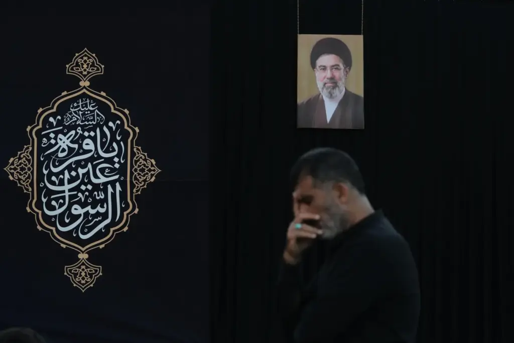 A man attends a sermon backdropped by a portrait of...